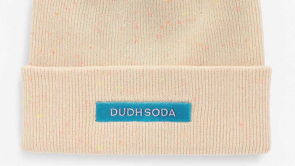 Beige beanie with a blue label on a light gray background